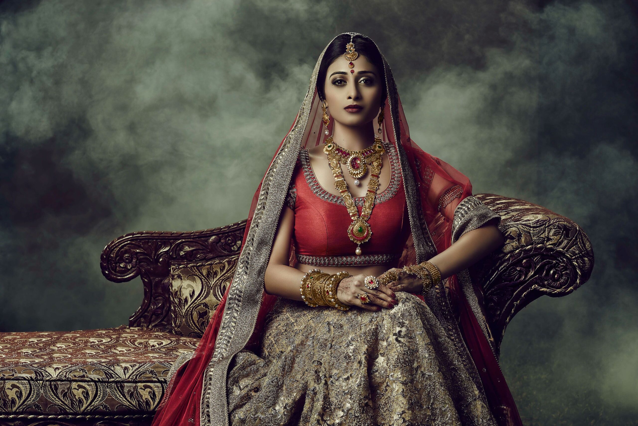 Young woman adorned in traditional Indian jewelry, wearing an ornate necklace, earrings, and bangles.